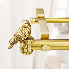 a gold bird is perched on the handle of a curtain