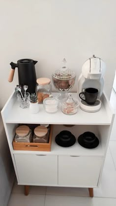 a white counter topped with lots of different types of food and coffee equipment on top of it