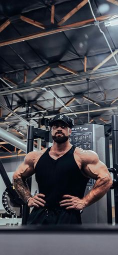 a man standing in front of a gym machine with his hands on his hips and looking at the camera