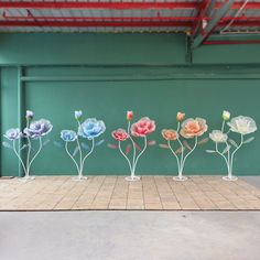 five different colored flowers are placed in vases on a tiled floor next to a green wall