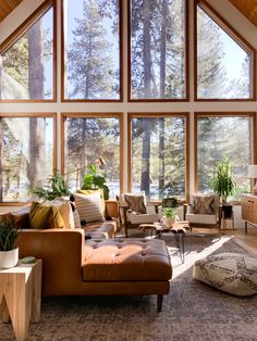 a living room filled with lots of furniture and large windows overlooking the trees in the background