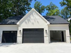 a white house with two garages and trees in the background