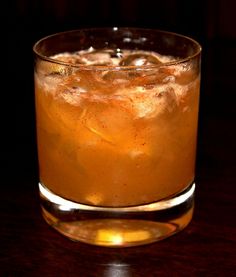 a close up of a drink in a glass on a table with a dark background