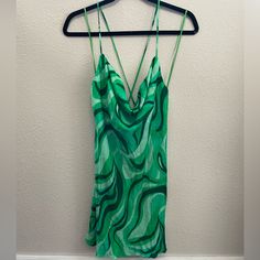 a green tank top hanging on a hanger in front of a wall with a white background