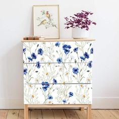 a white dresser with blue flowers painted on it