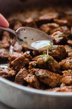 a spoon is being used to stir some meat