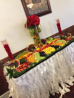 a table topped with fruit and flowers on top of a white cloth covered tablecloth