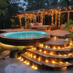 a deck with lights around it and a pool in the middle surrounded by wood steps