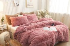 a bed covered in pink fluffy blankets and pillows