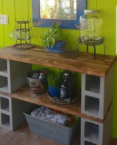 a shelf with some plants on it in front of a green wall and blue mirror