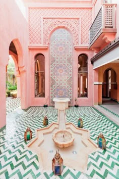 a fountain in the middle of a room with pink walls and green tiles on the floor