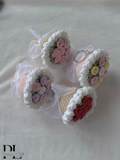 four crocheted wedding rings with flowers in them on a white cloth covered surface