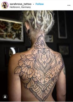 the back of a woman's neck with an intricate tattoo design on her chest