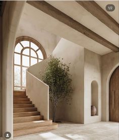 a tree is in the middle of a room with stairs and arched windows on either side