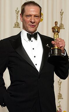 a man in a tuxedo holding up an award for best performance by an actor