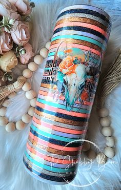 the tumbler is decorated with colorful stripes and an image of a cow's skull