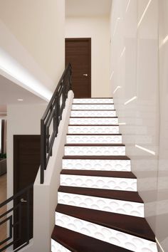 a stair case with white flowers painted on the side and black handrails, along with a brown door