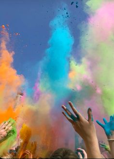 people throwing colored powder in the air at an outdoor event with their hands raised up