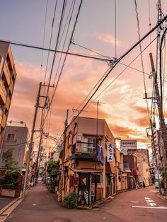 an alley way with many buildings and power lines above it at sunset or dawn in the city