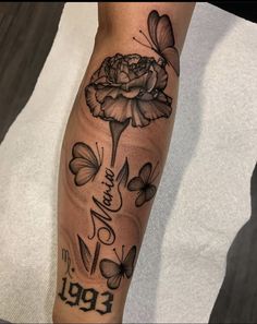 a woman's leg with tattoos and flowers on her arm, which has butterflies around it