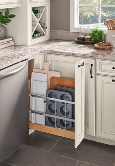 a kitchen with white cabinets and granite counter tops, an open dishwasher is in the corner