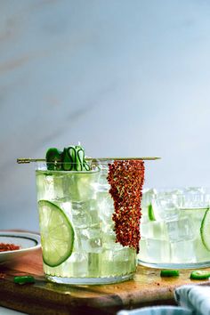 two glasses filled with limeade and garnish on top of a cutting board