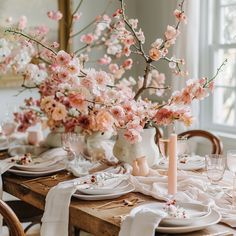 the table is set with pink flowers and plates