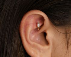 a woman's ear is shown with a single diamond in the middle and two smaller diamonds at the bottom