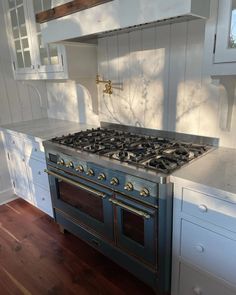 a stove top oven sitting inside of a kitchen next to white cabinets and counter tops