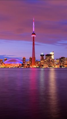 the city skyline is lit up at night, with lights reflecting off the water and buildings in the background