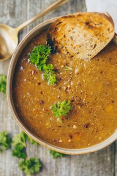 a bowl of soup with bread and parsley