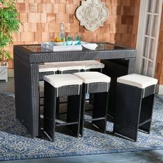 an outdoor table with four stools and a plant in the corner next to it