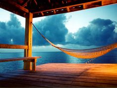 a hammock hanging from the side of a wooden pier