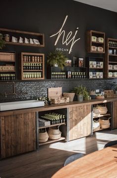 the inside of a restaurant with wooden shelves and plants on display behind the counter area