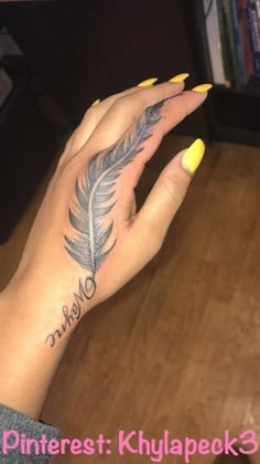 a woman's hand with a feather tattoo on her left wrist and yellow nail polish