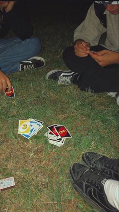 several people sitting on the grass playing with cards and dices in front of them