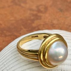 New, but old pieces, never worn, recently acquired from a premiere jeweler located in Minneapolis, MN for many years- a rare opportunity. 18KT yellow gold genuine, double bezel, round, mabe pearl ring Size 6.50 Sizable by us for a fee or your local jeweler Weight: 12.2 grams Band width: 3mm in back 11.50~12mm round mabe pearl Stamped 18k Double Bezel Ring, Luxury Pearl Ring With Bezel Setting, Timeless Gold Dome Ring With Cabochon, Mabe Pearl Rings, Classic Domed Collectible Jewelry, Classic Cabochon Pearl Ring For Formal Occasions, Classic Formal Pearl Ring With Cabochon, Anniversary Yellow Gold Pearl Ring With Cabochon, Formal Cabochon Pearl Ring