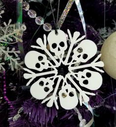 a snowflake ornament hanging from a christmas tree with purple and silver ornaments