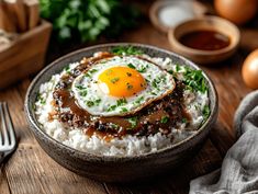 an egg on top of rice in a bowl next to eggs and other food items