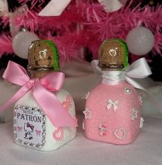 two small bottles with pink and white designs on them sitting next to a pink christmas tree