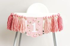 a chair decorated with pink tassels and a number one banner hanging from the back