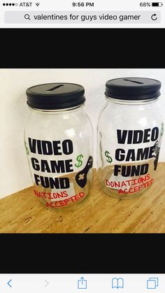 two glass jars with video game fund stickers on them sitting on a wooden table