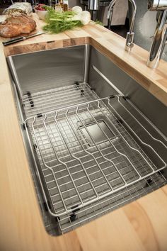 a stainless steel sink in a kitchen with wooden counter tops and an oven rack on the left side