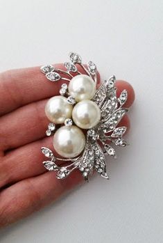 A pearl brooch is a decorative piece that accents and forms the shape of a neckline. A Pearl brooch is also known as a corsage pin. This brooch is a perfect accessory for the fall season. It features a large pearl and leaves with a rhinestones accent. It's the ideal way to add elegance and style to your everyday wear. ⭐   6 cm x 5m that is about 2.4" x 2" ⭐   Lead, cadmium, and nickel free ⭐   Pearl sizes are 14mm and 10mm ⭐   Pearl color is a soft ivory ⭐   Seriously unique for more brooches & pins https://www.etsy.com/shop/okqSupply?ref=seller-platform-mcnav§ion_id=27262035 Bridal Rhinestone Headpiece, Brooch Bouquet Diy, Wedding Brooches, Brooch Corsage, Bridal Brooch Bouquet, Rhinestone Headpiece, Wedding Brooch Bouquets, Corsage Pins, Bridal Accessories Jewelry