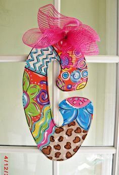 a colorful door hanger decorated with an animal print and a pink bow on the top