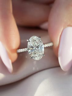 a woman's hand holding a ring with a large diamond on the middle of it