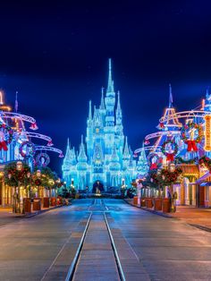 the main street in disney world lit up at night with christmas decorations and lights all around