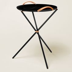 a black tray with wooden handles sitting on top of a metal tripod stand that is bent to the side