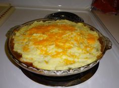 a pie sitting on top of a stove next to a white countertop covered in cheese