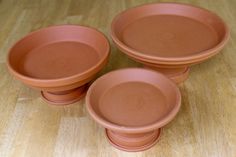 three clay bowls sitting on top of a wooden table